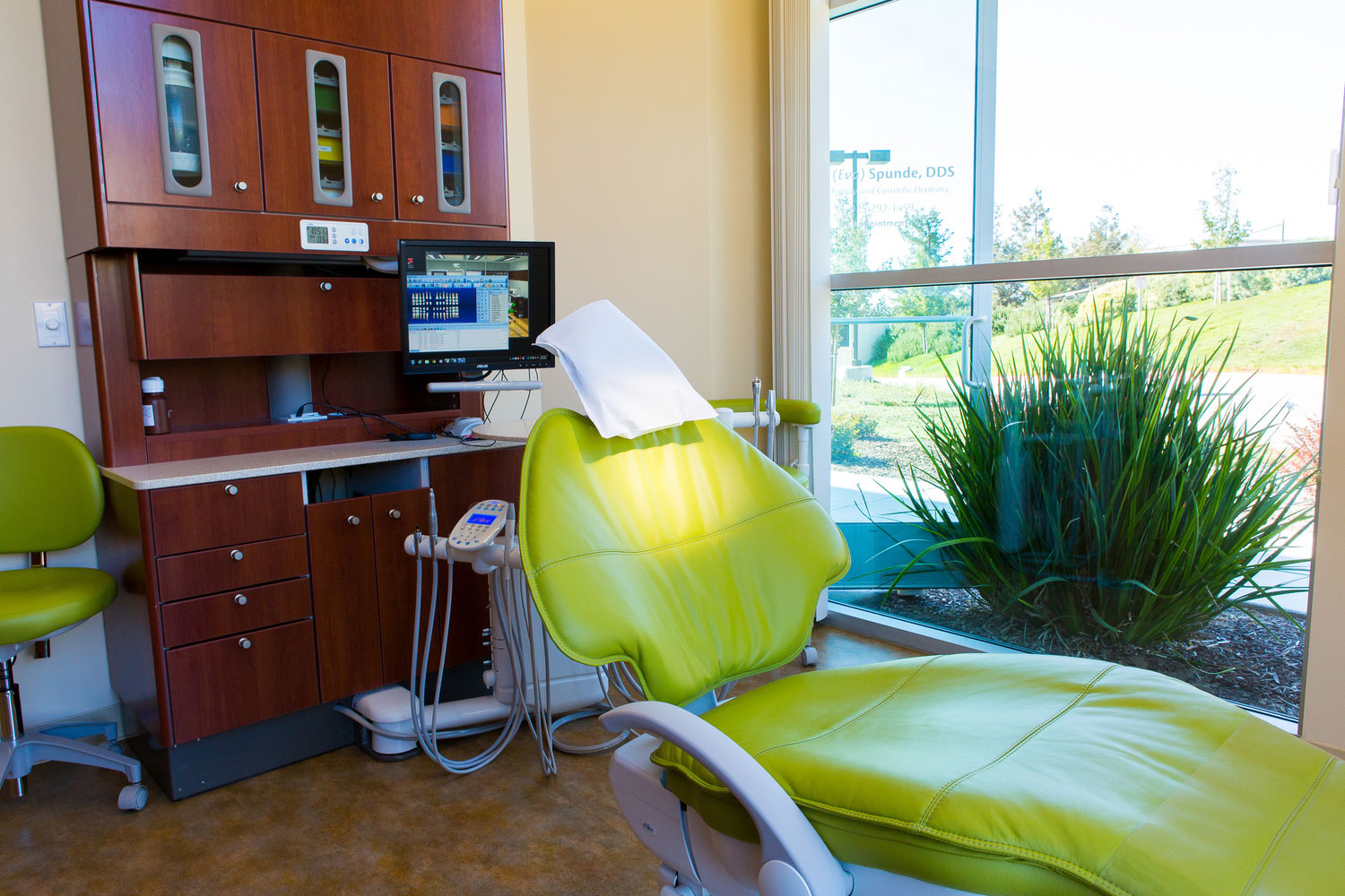 The image shows a dental office interior with modern equipment, including a dental chair and a computer screen displaying patient information.